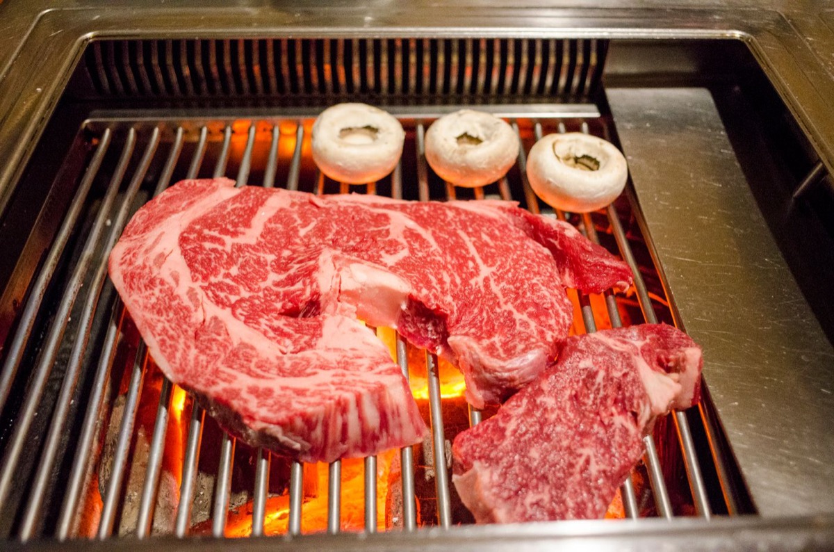 Marbled Fullblood Wagyu steaks searing over open fire
